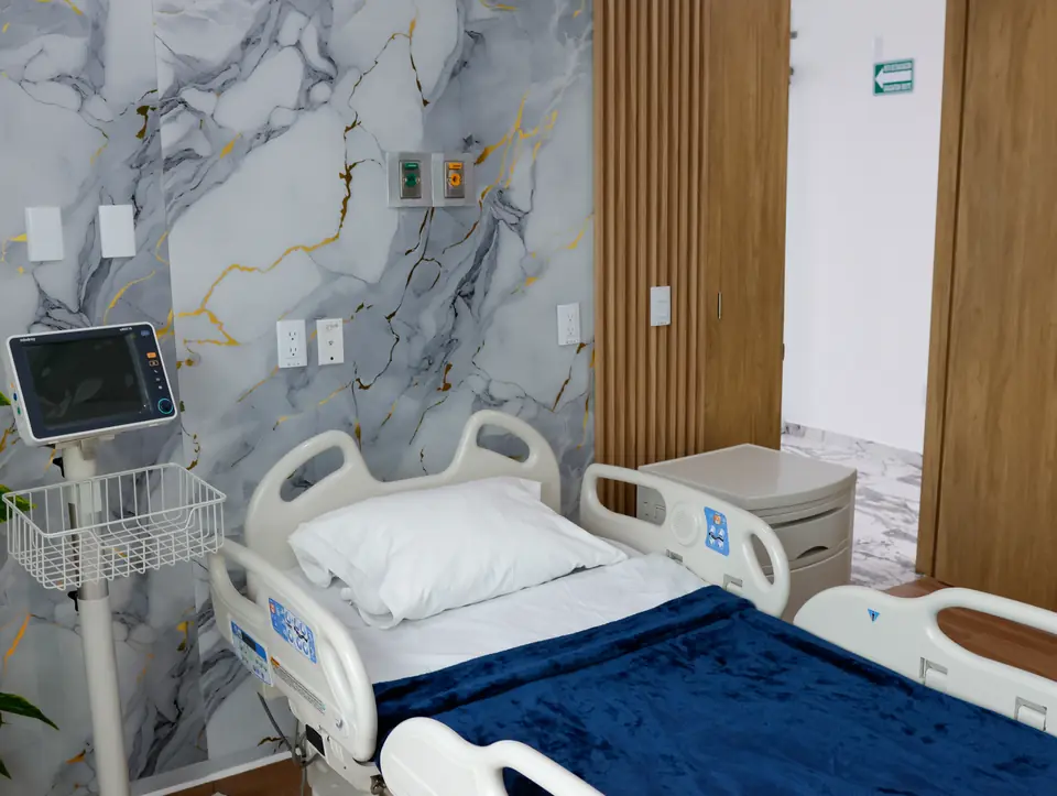 Cabecera de habitación con monitor de signos vitales y muro de mármol con vetas doradas