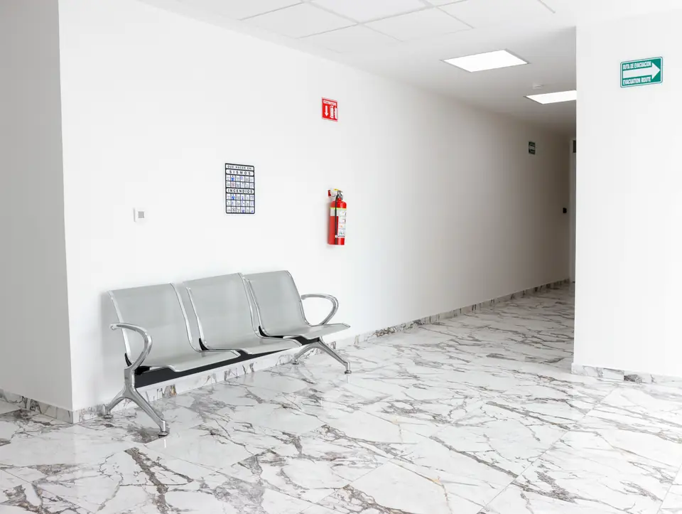 Pasillo con bancas de espera, señalización y piso de mármol
